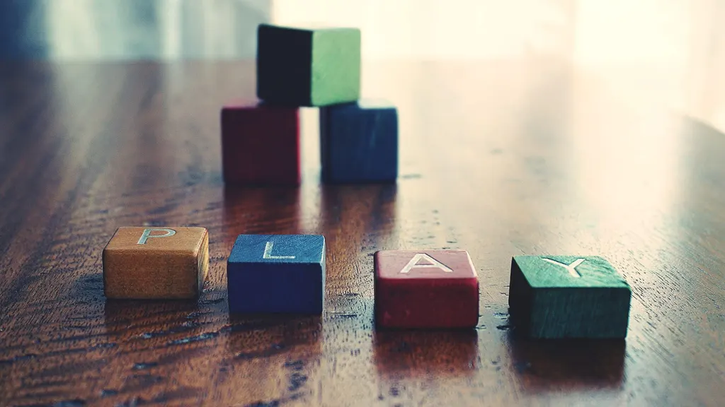 Wooden alphabet blocks spelling PLAY on a polished wood floor